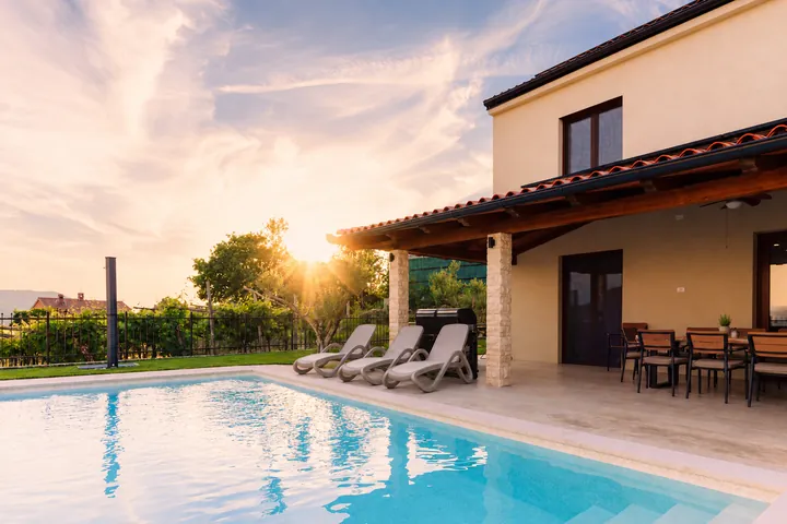 Villa LEA at sunset: saltwater pool, loungers and covered terrace among the vineyards of Marezige